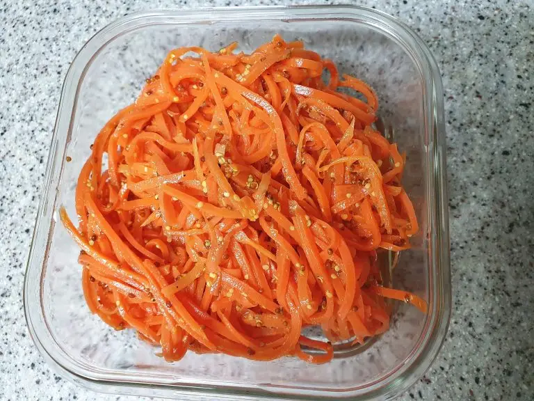 Salată portocalie din morcovi rași, așezată pe farfurie.