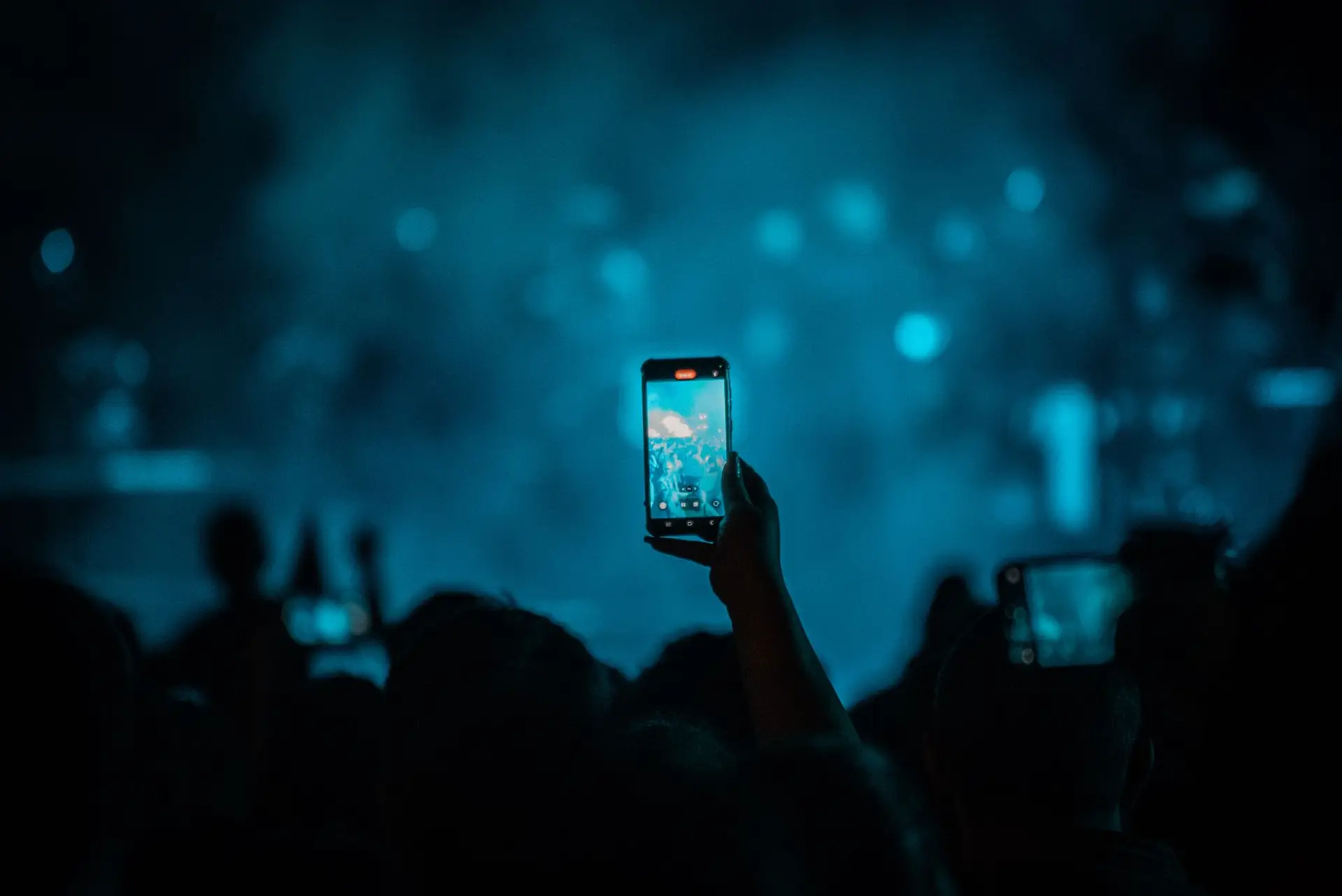 Colourful concert stage lights and an audience holding up phones in Bucharest.